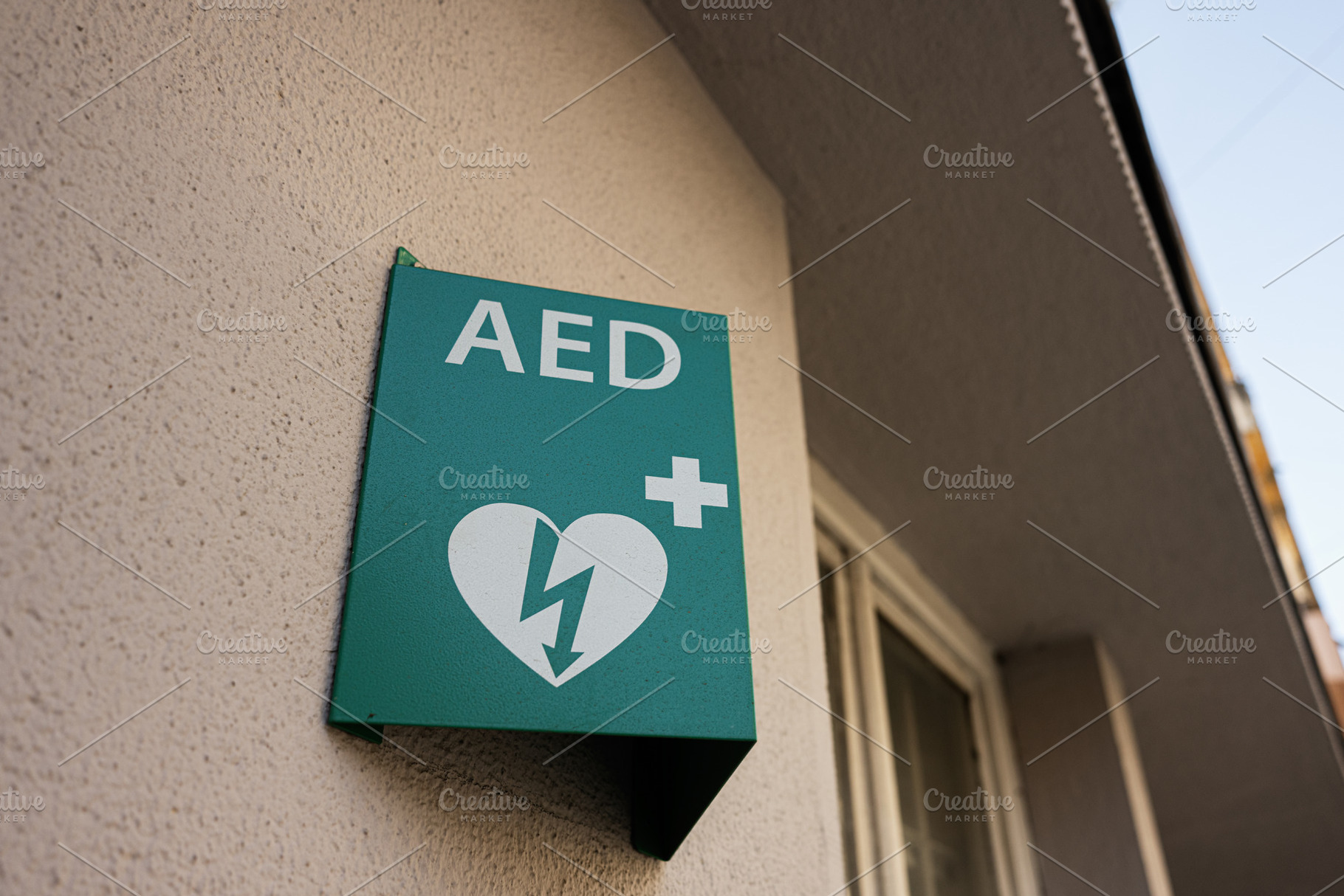 Green AED sign on wall indicating defibrillator location, a Photo by AS photostudio