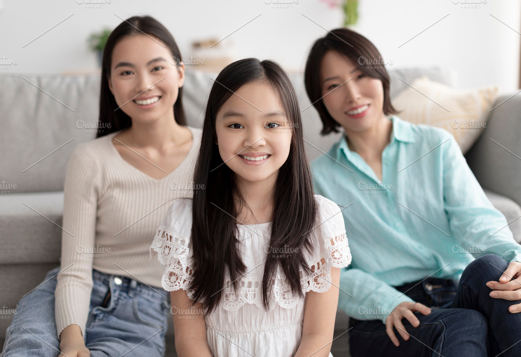 Portrait of little Asian girl spending time with ger mother and granny in livin, a Photo by Prostock-Studio