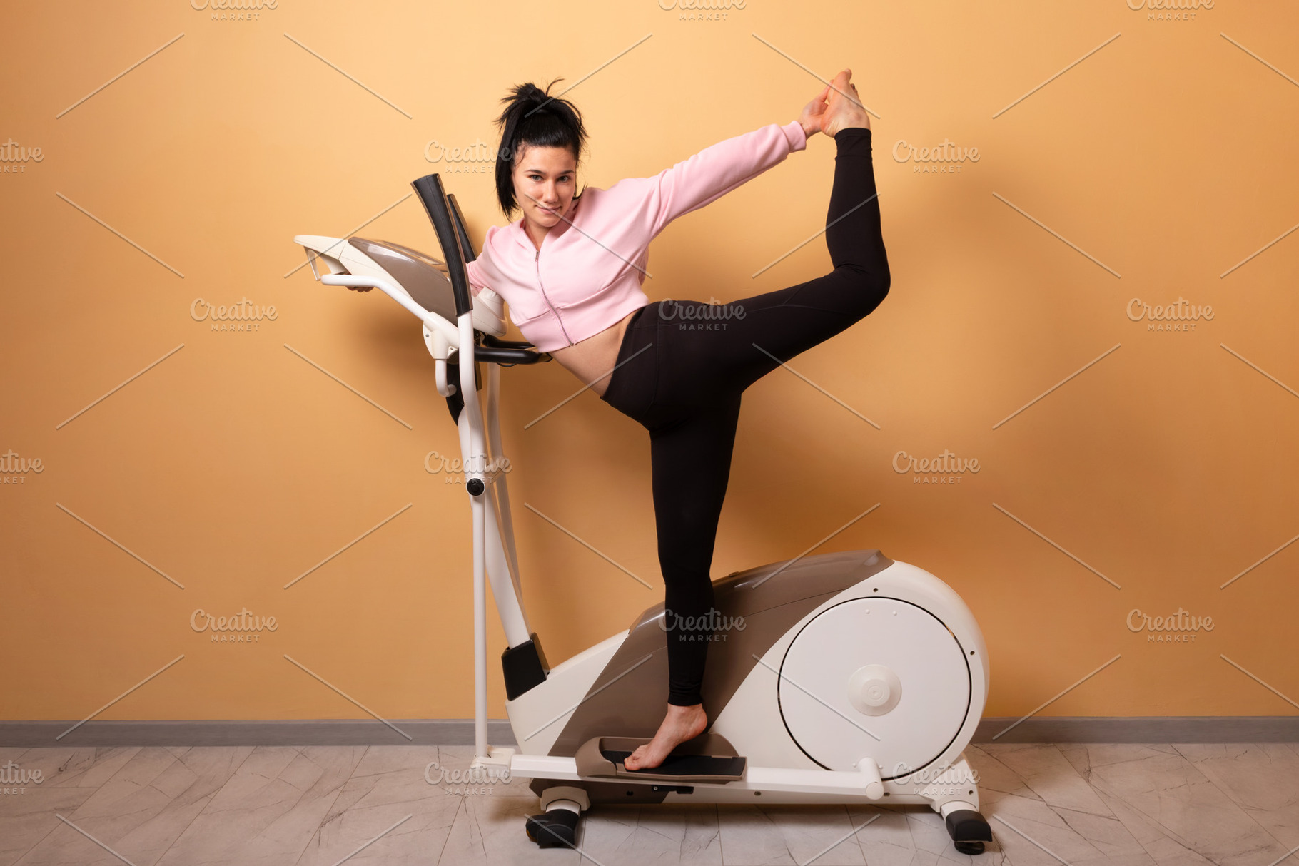 Young woman in sportswear stretching on a stationary bike agains, a Person Photo by Ales Munt