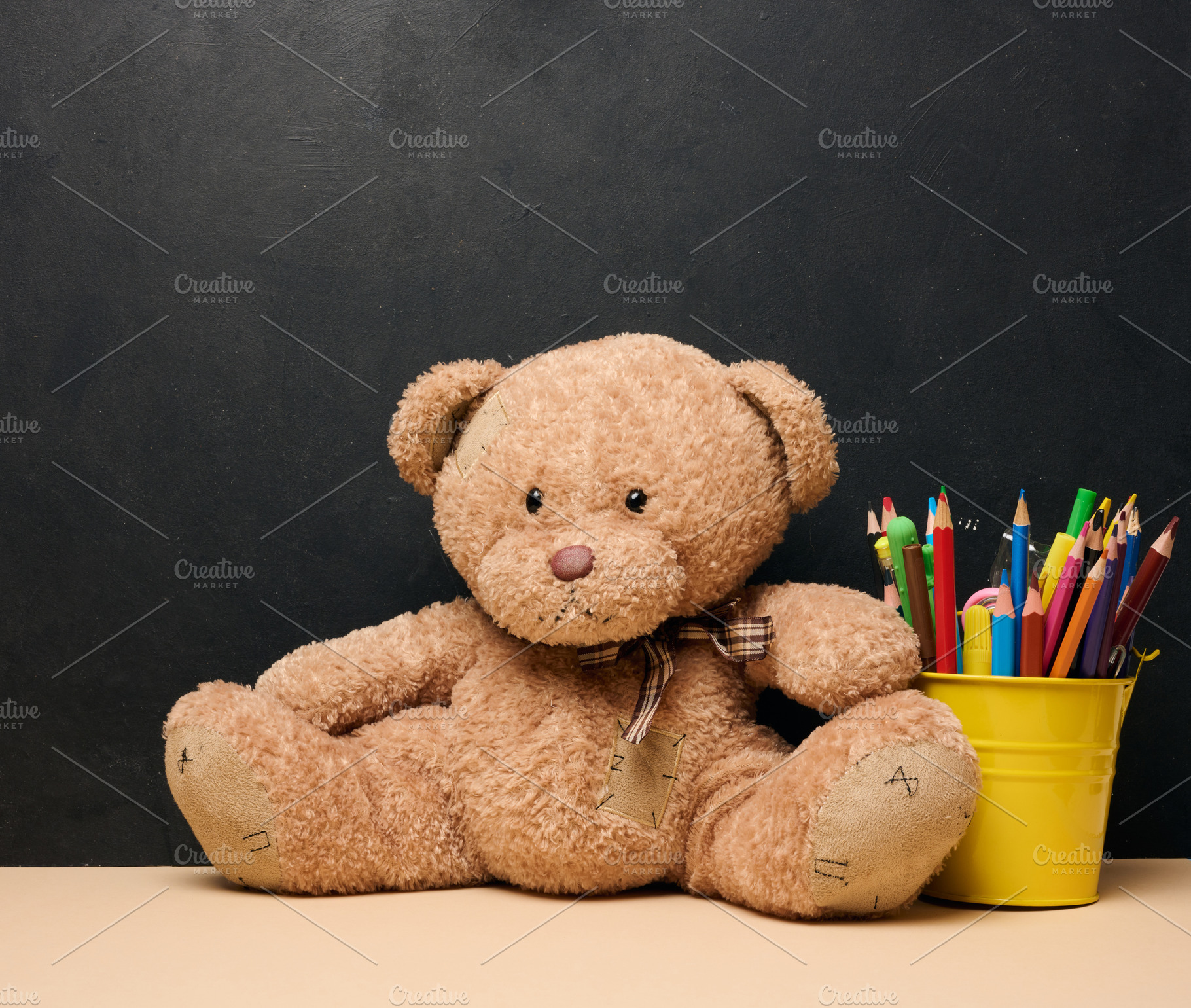 A brown teddy bear sits next to a yellow bucket filled with colo, a School & Education Photo by ndanko