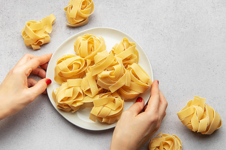 Chef placing uncooked pasta on white plate for italian cuisine, a Food & Drink Photo by Olena Rudo