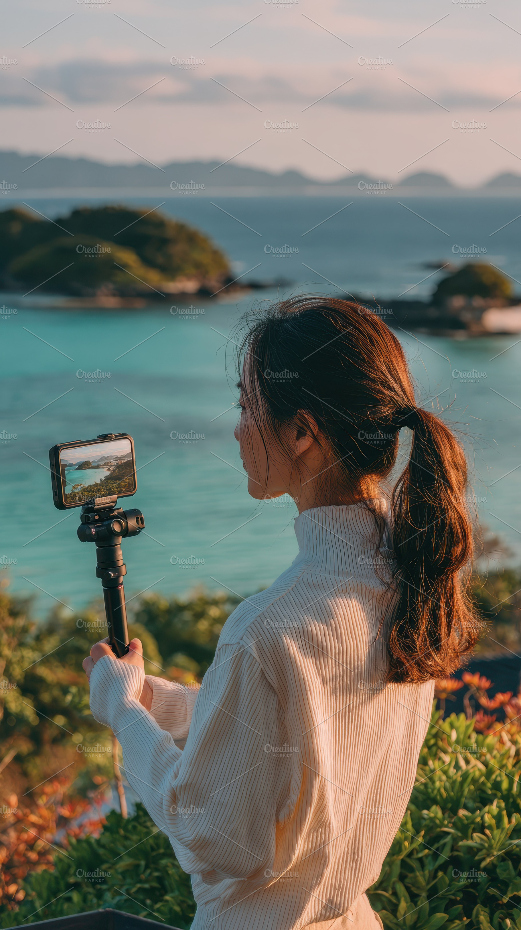 Woman filming scenic ocean view with, a Photo by Pixeness Studio