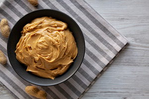 Organic Creamy Peanut Butter in a Bowl, top view. Copy space., a Food & Drink Photo by LiudmylaChuhunova