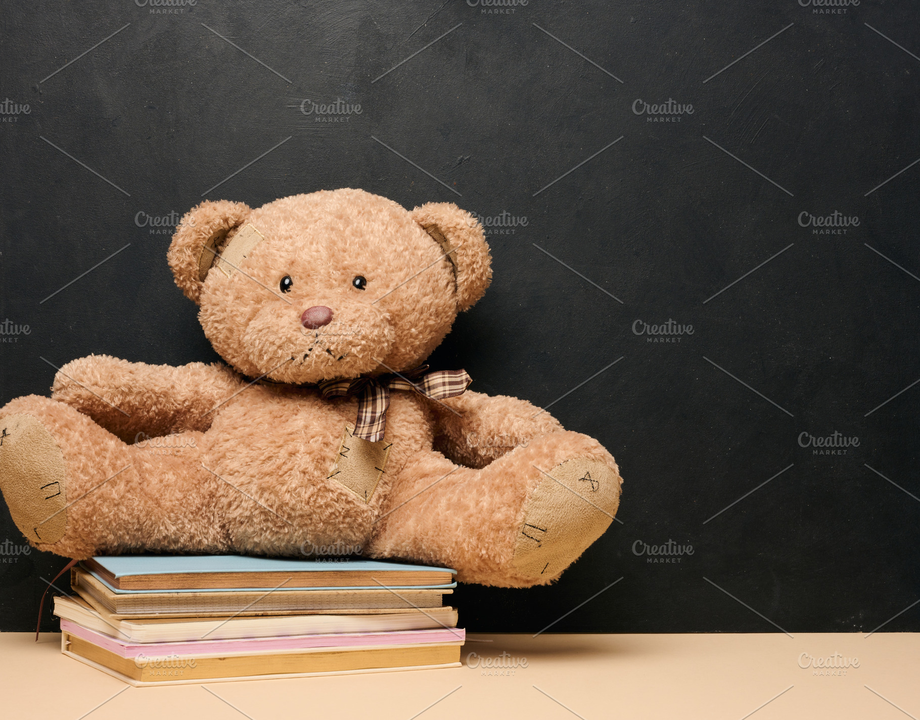 Brown teddy bear sitting on a stack of colorful books symbolizin, a School & Education Photo by ndanko