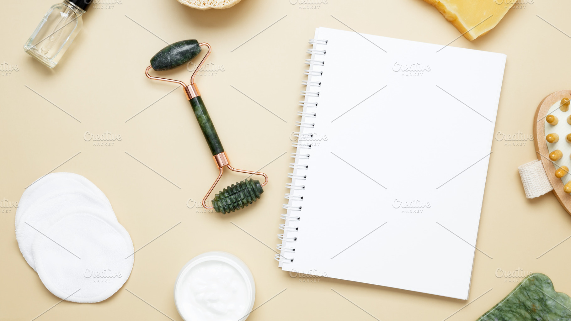 Flat lay of skincare essentials with notebook mockup including marble face roll, a Photo by matucha