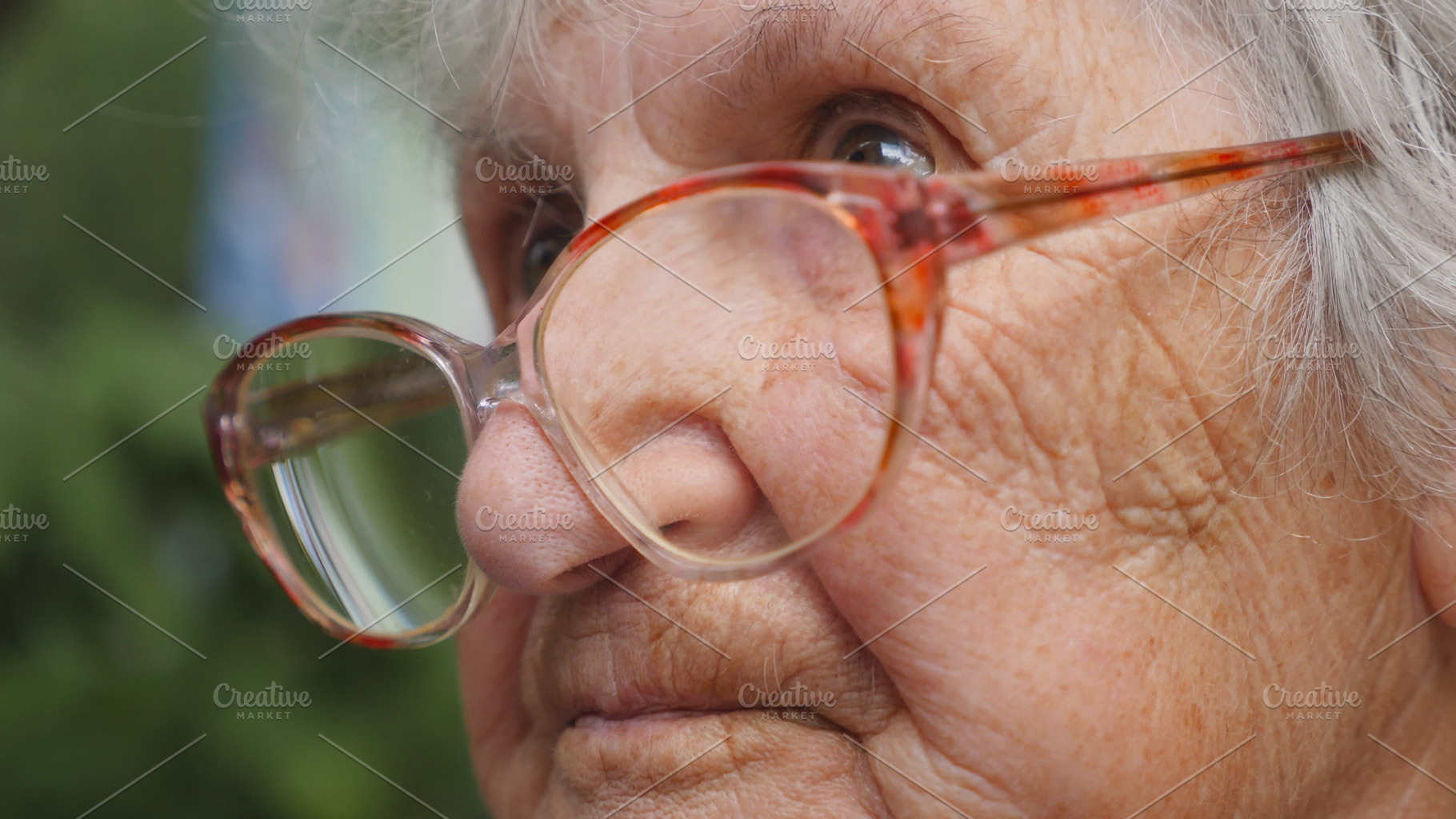 Old woman in glasses looking forward. Granny wearing eyeglasses outside. Portrait of grandmother outdoor. Close up Side view Slow motion, a Person Photo by Footage Autor