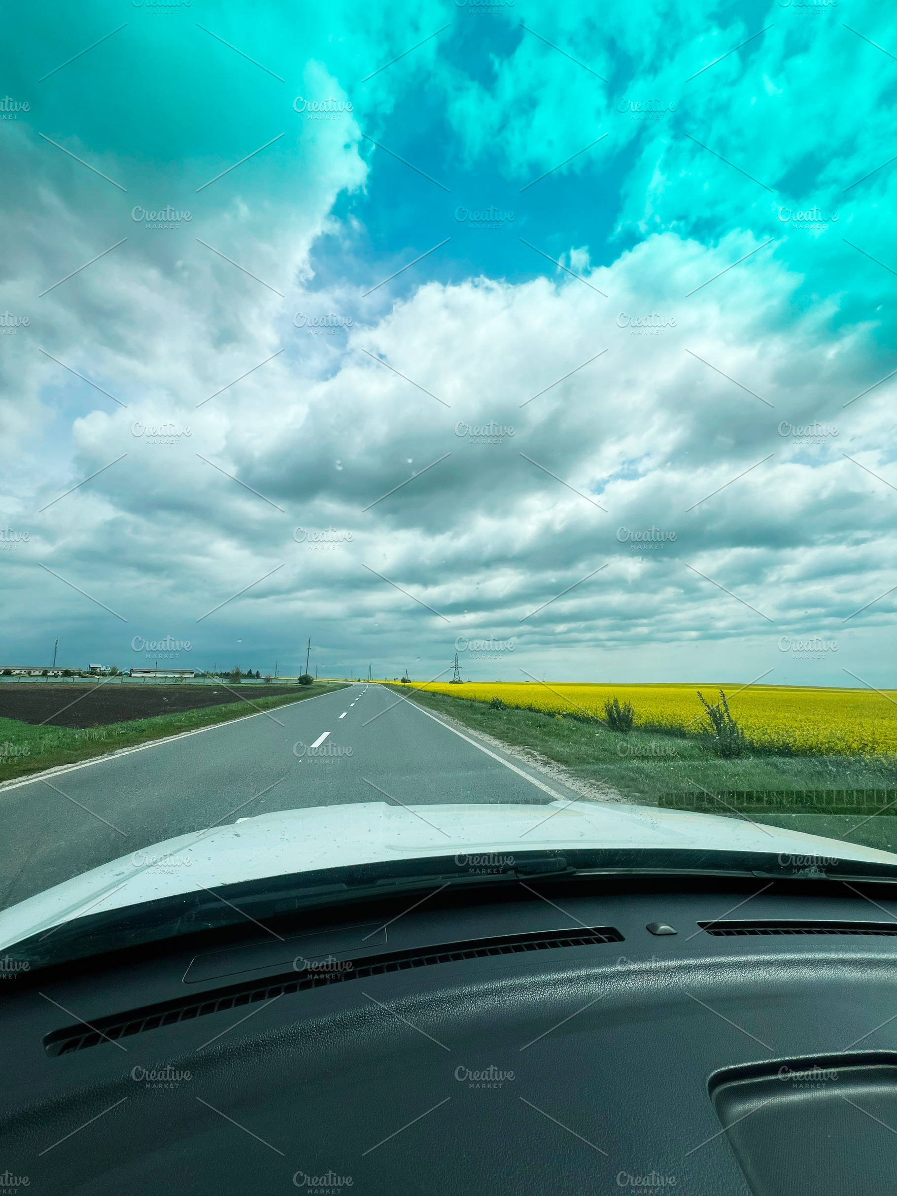 Scenic rural road with a vibrant yellow field under a blue cloudy sky, a Photo by AS photostudio