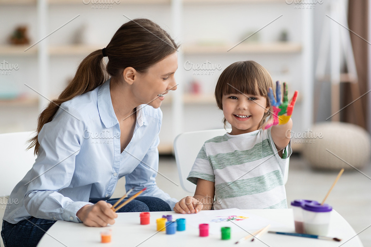 Happy little boy showing colorful palm, smiling to camera, sitting with profess, a Photo by Prostock-Studio (Photo 1 of 2)