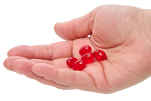 Red gel capsules or vitamins on a person's palm against, a Health & Medical Photo by ndanko