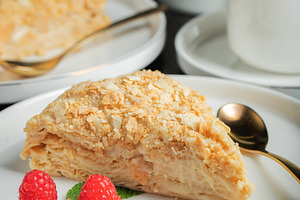 Sliced Napoleon cake on a white wooden table. Classic dessert, a Food & Drink Photo by Budarinphoto