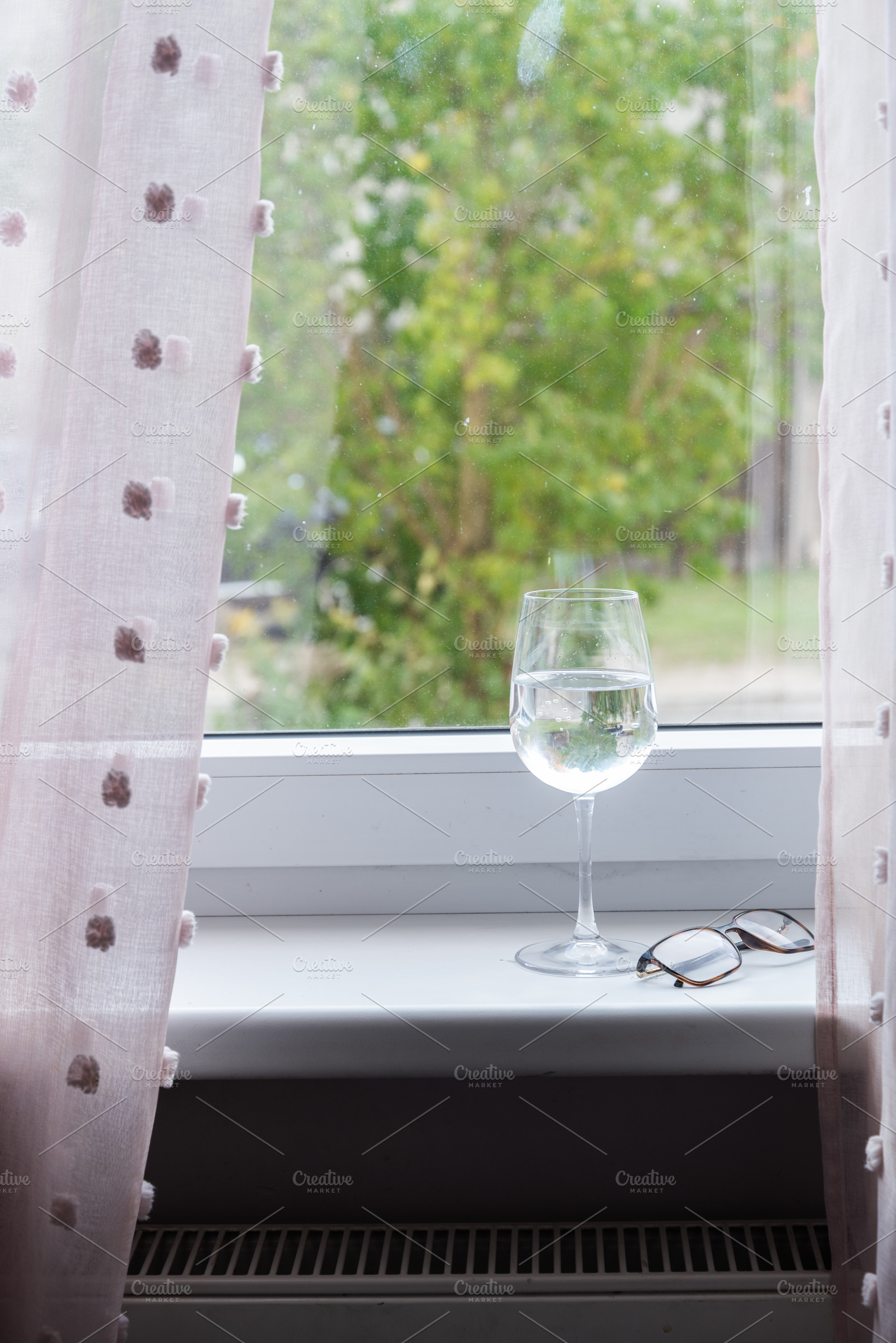 Wine glass and eyeglasses on windowsill in natural light, an Industrial Photo by MDBildes