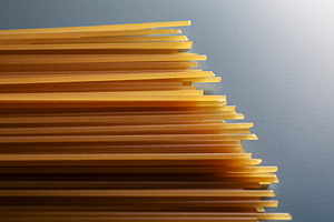 Dry spaghetti pasta noodles forming a pattern on a gray background, raw Italian, a Photo by Studio ANNA