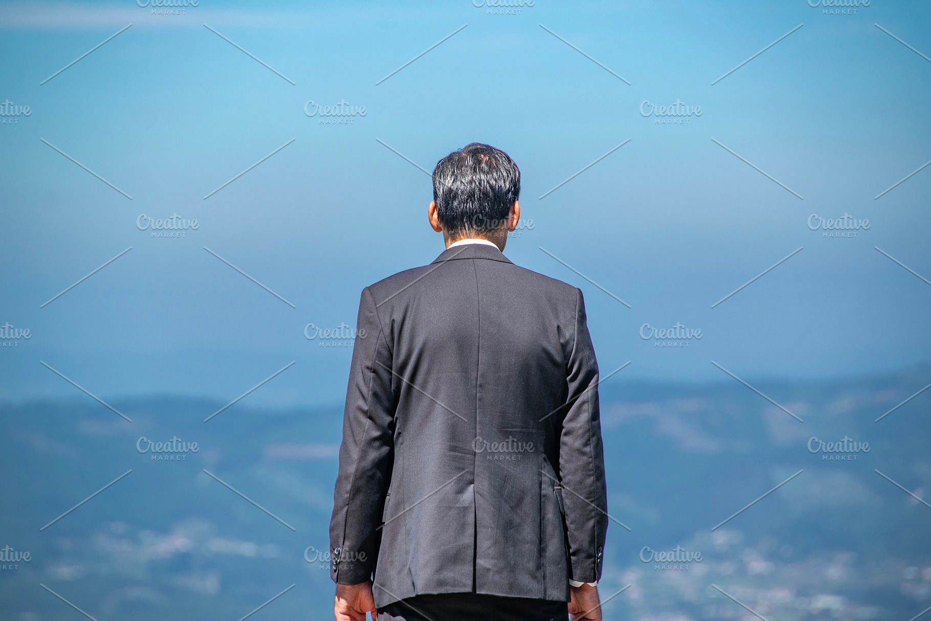 Man in suit facing distant mountains alone, a Person Photo by DanFLCreativo
