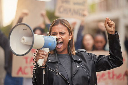 Justice, megaphone and shouting with woman in protest for equality, freedom and support for change. Global fight, social and future with girl in crowd for human rights, community and revolution, a Photo by Peopleimages.com