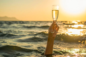 Arm raising a champagne glass from the middle of the sea, a Food & Drink Photo by DanFLCreativo