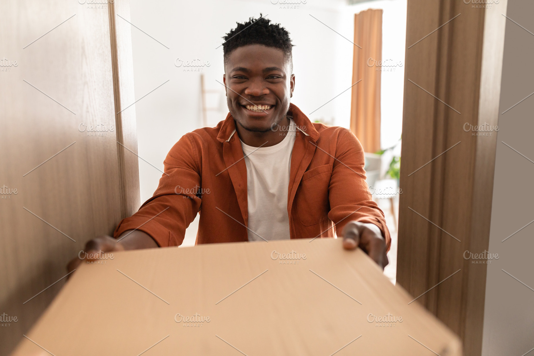 African Guy Receiving Pizza Box In Opened Door At Home, a Photo by Prostock-Studio