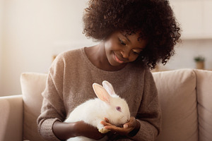 Young afro woman holding rabbit, a Person Photo by DanFLCreativo