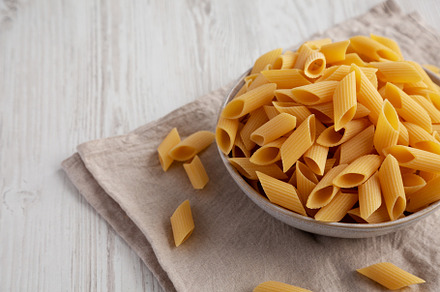 Raw Organic Dry Pennoni Pasta in a Bowl, side view. Space for te, a Food & Drink Photo by LiudmylaChuhunova