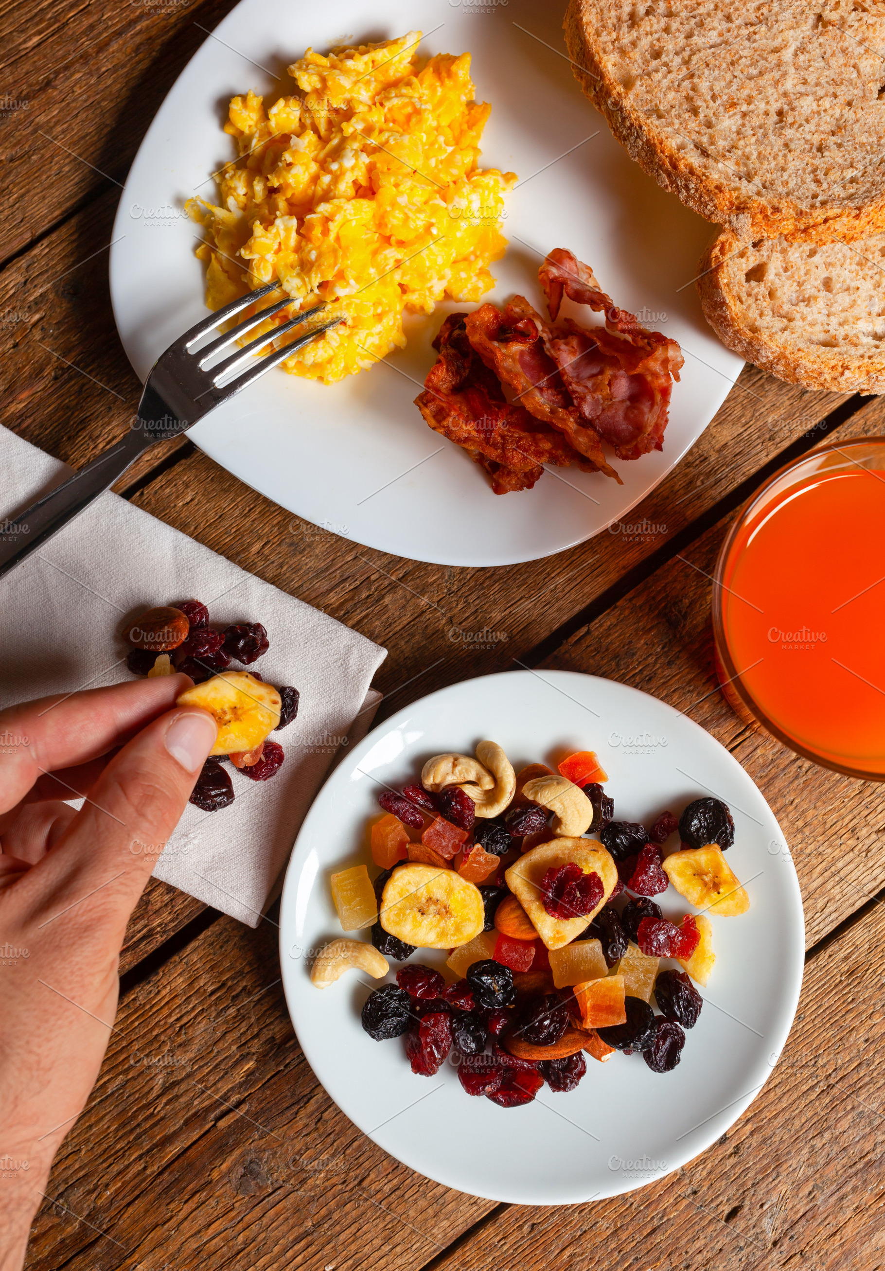 Hand Picking Dried Fruit from Plate, Scrambled Eggs with Bacon and Orange Juice, a Food & Drink Photo by Antonio Gravante Market