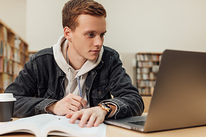 Male student in a library reading, a Person Photo by Artem Varnitsin