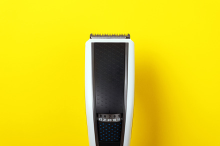 Close-up of a modern electric hair clipper on a vibrant yellow b