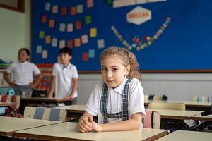 Elementary school girl sitting alone at her desk in a classroom, a School & Education Photo by etorres69
