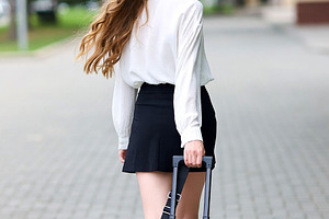 beautiful young woman walks on sideway in city center with suitc, a Photo by WorldOfPhotos