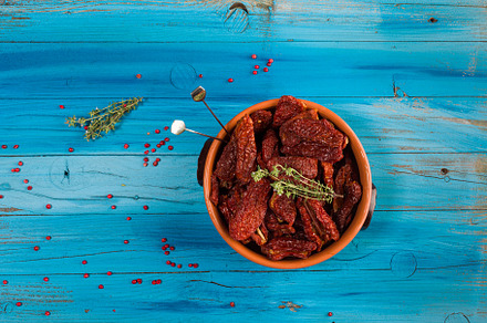 Mediterranean dried tomatoes inside a bowl on blue rustic wooden, a Food & Drink Photo by Bepslabor