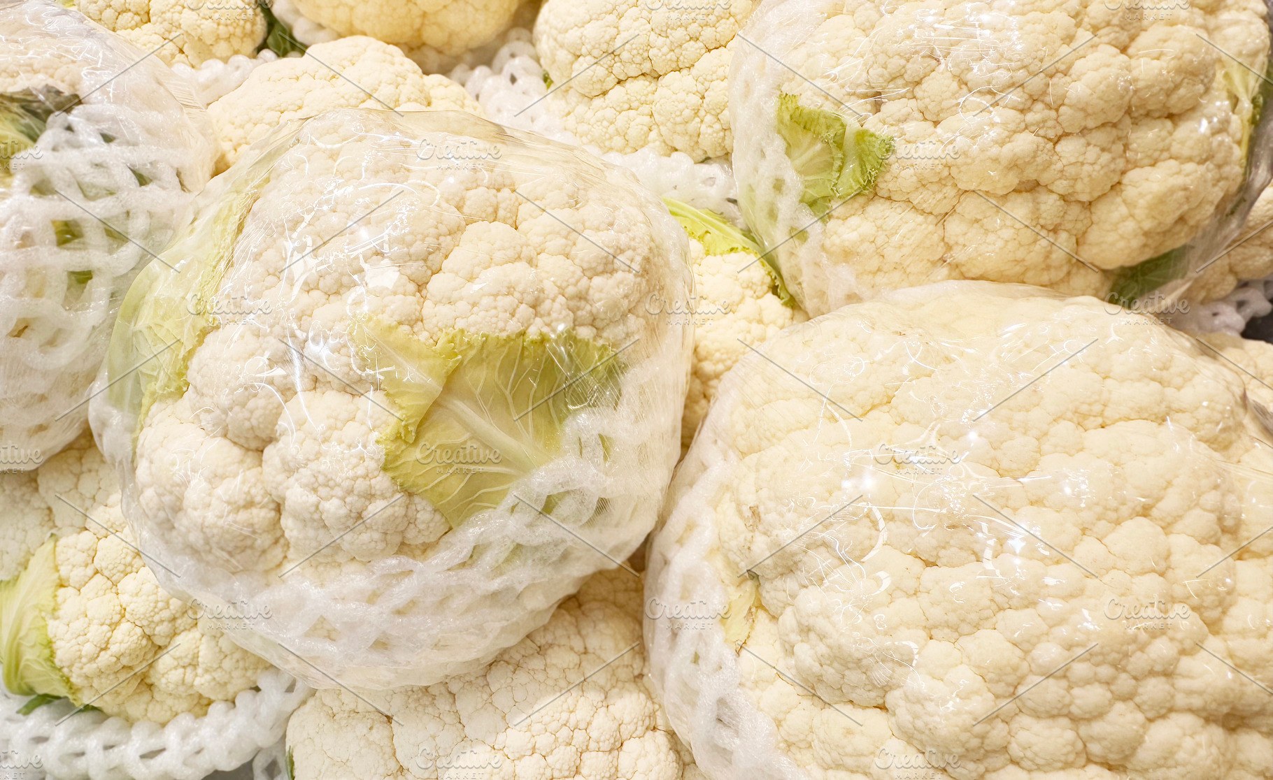 Cauliflower pile in plastic wrap, a Food & Drink Photo by ArtBackground