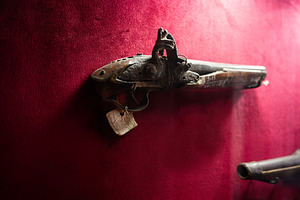 Vintage antique musket displayed against a vibrant red backdrop in close view, a Photo by AS photostudio