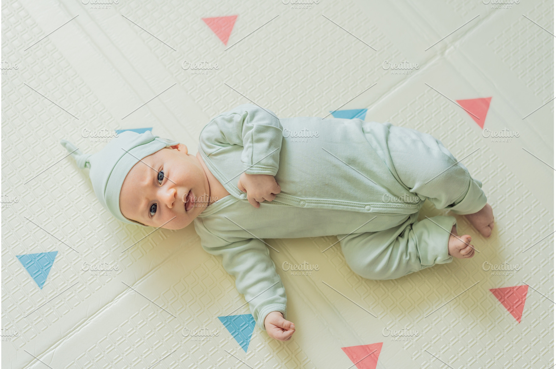 Adorable baby in a green hat lying, a Person Photo by Elizaveta Galitskaya