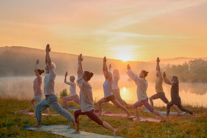 People practicing yoga in harmony at tranquil sunset landscape, a Health & Medical Photo by DanFLCreativo