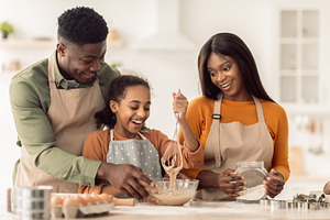 African American Family Making Dough Mixing Ingredients Baking In Kitchen, a Photo by Prostock-Studio
