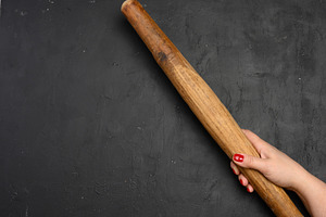Female hand holding a vertical antique wooden rolling pin agains, a Food & Drink Photo by ndanko