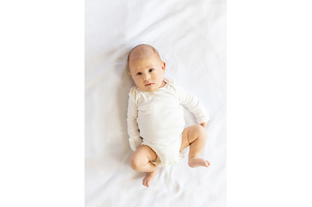 A newborn baby lies on a white bed, a Person Photo by yanadjana