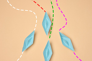 Top view of four blue paper boats following different dotted lin, a Business Photo by ndanko