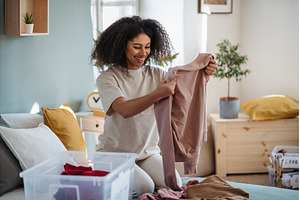 Young woman sorting wardrobe indoors