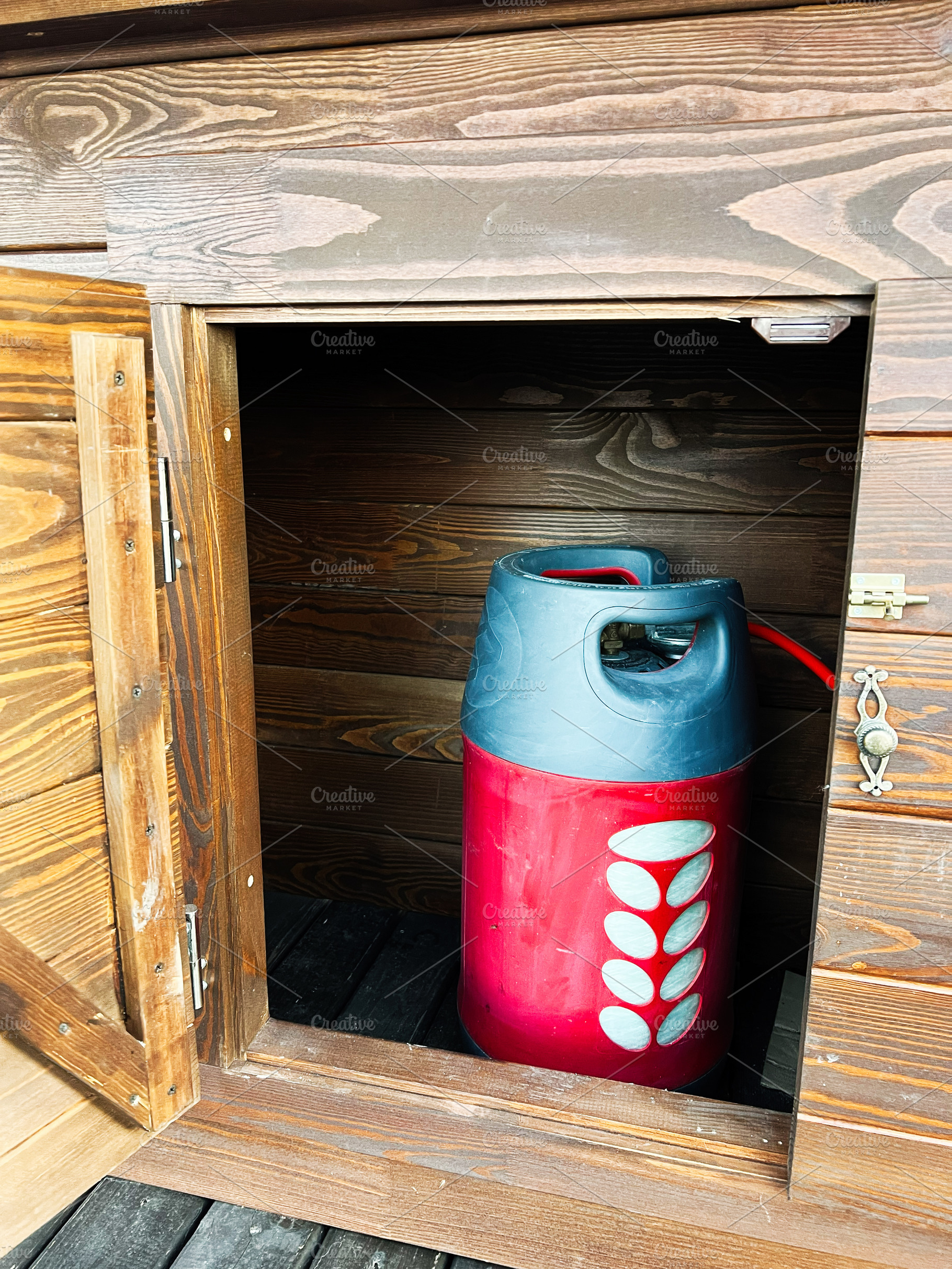 Wooden cupboard with a red gas cylinder safely stored inside, a Photo by AS photostudio