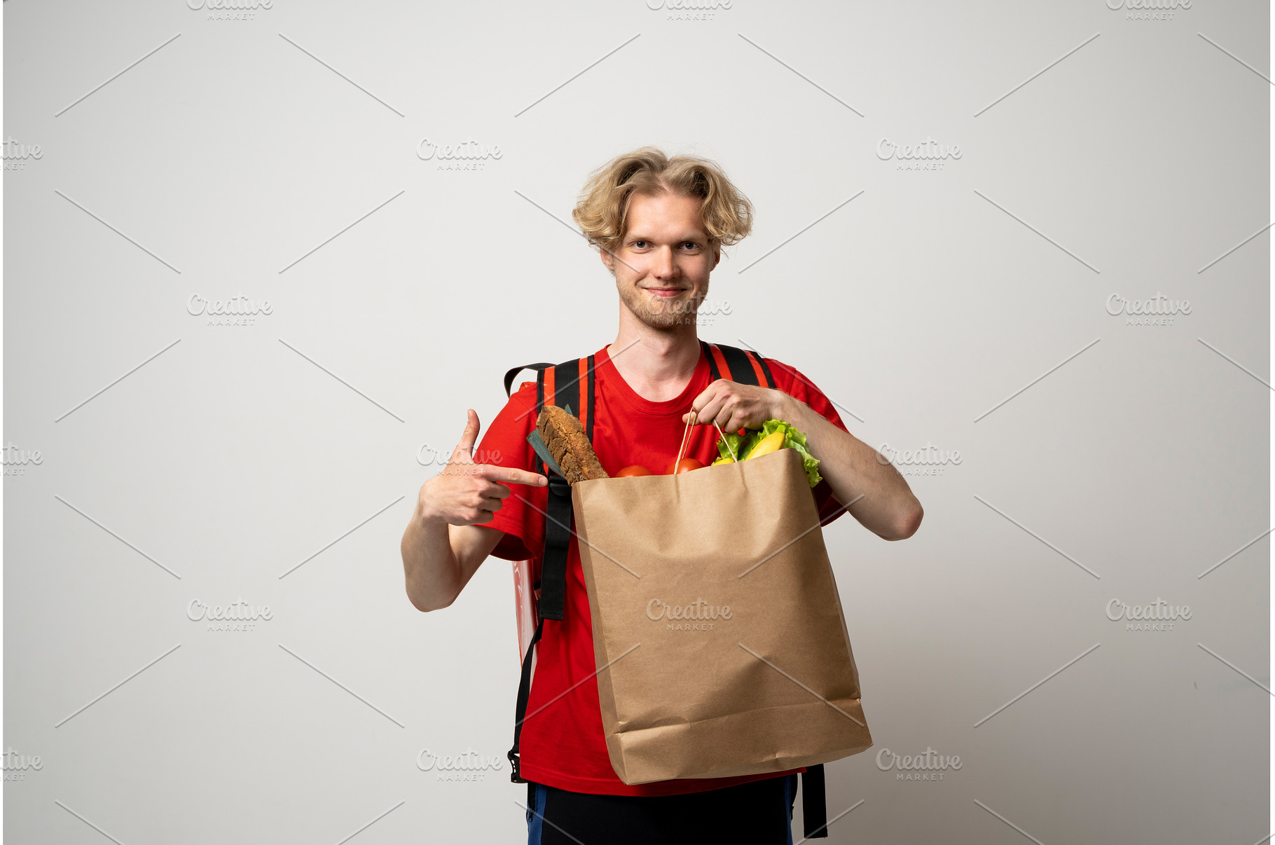 Young delivery man in a red uniform, a Person Photo by volodymyrshtun13795
