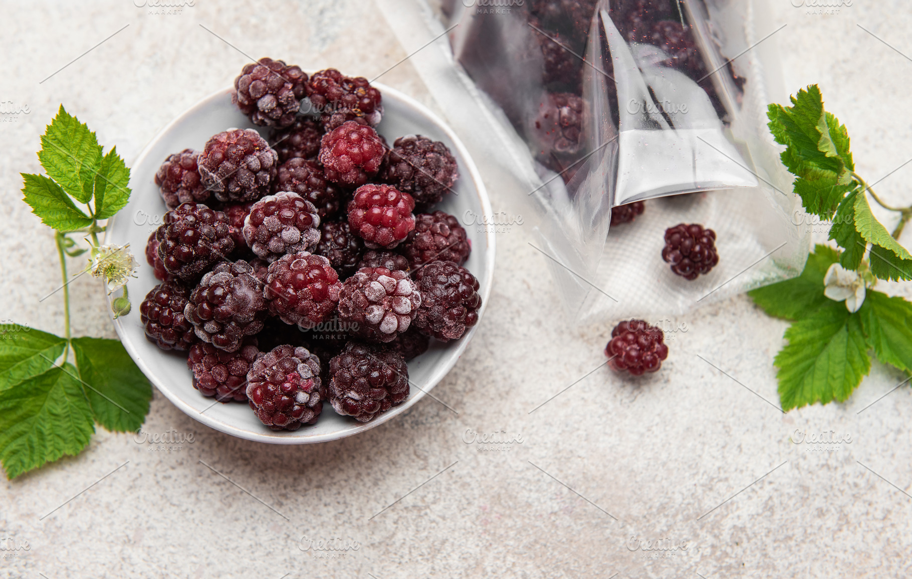 Frozen blackberries spilling from a bag into a bowl, a Food & Drink Photo by Olena Rudo