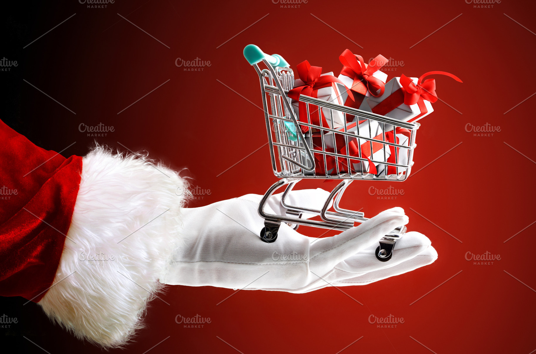 Santa's hand holding shopping cart full of gifts isolated red, a Person Photo by Davizro's Market