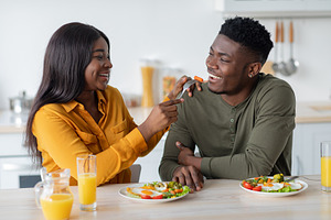 Cheerful Black Couple Fooling While Having Breakfast In Kitchen Together, a Photo by Prostock-Studio