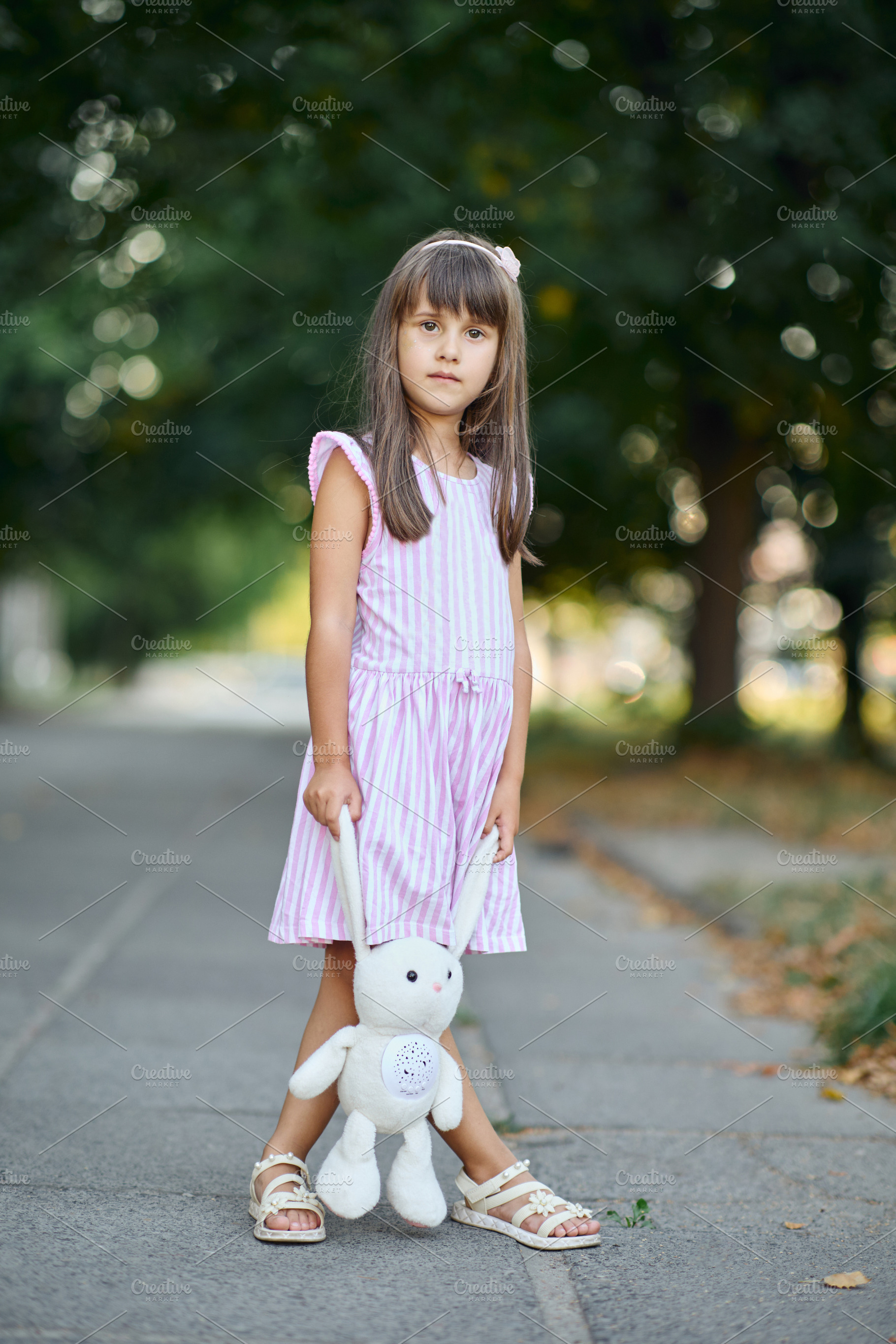 Full length portrait of a cute little girl standing on a sidewalk holding a plu, a Person Photo by Rohan Photography