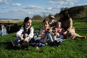 Family picnic by the river with children and mother sharing tea and pastries on, a Person Photo by AS photostudio