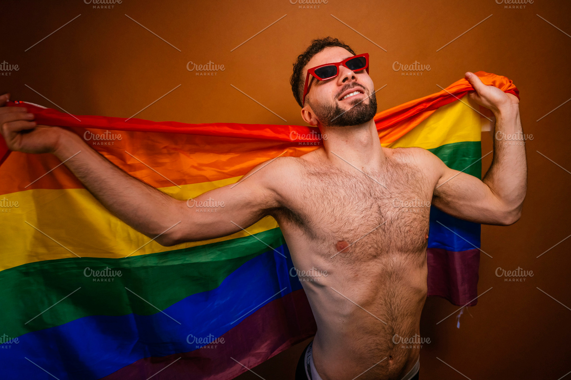 Shirtless man celebrating pride month holding rainbow flag, a Photo by karrastock