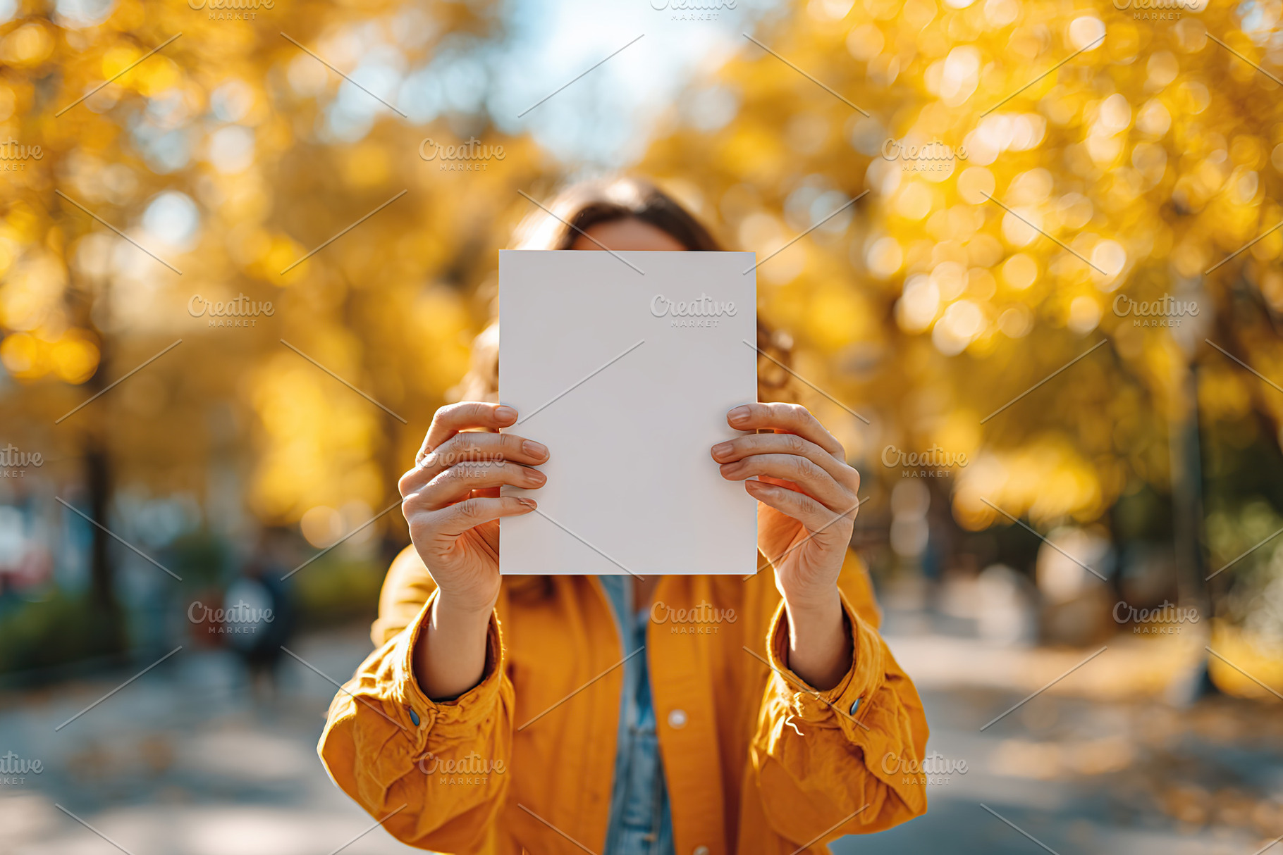 Person holding blank vertical poster in autumn park with yellow leaves, a Photo by AlyaAnd