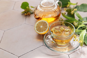 Linden herbal tea brewing with fresh lemon and natural flowers, a Food & Drink Photo by Olena Rudo