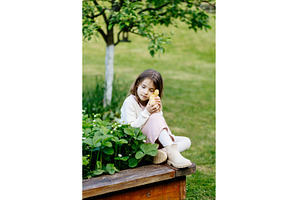 Young girl in garden playing with, an Animal Photo by HalfPoint