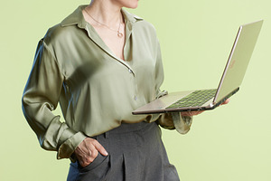 Professional woman with laptop on green background, a Person Photo by Alliance Images