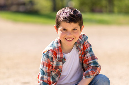 Young boy squatting on a gravel path in a sunny park., a Person Photo by RF Images